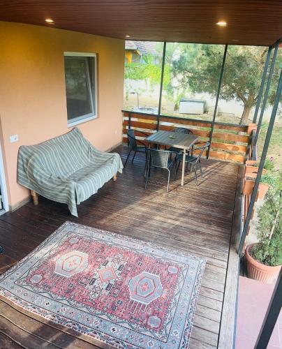 a deck with a bed and a table and a rug at Tenisz vendégház in Ordacsehi