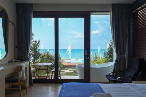 a bedroom with a tub and a view of the ocean at เดอะซีน คาบาน่า บีช รีสอร์ท ขนอม The Scene Cabana Beach Resort Khanom in Ban Plau