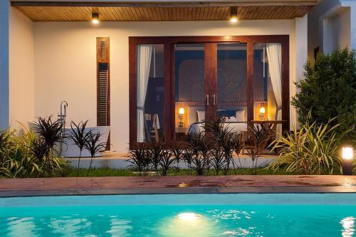 a house with a swimming pool in front of a house at เดอะซีน คาบาน่า บีช รีสอร์ท ขนอม The Scene Cabana Beach Resort Khanom in Ban Plau