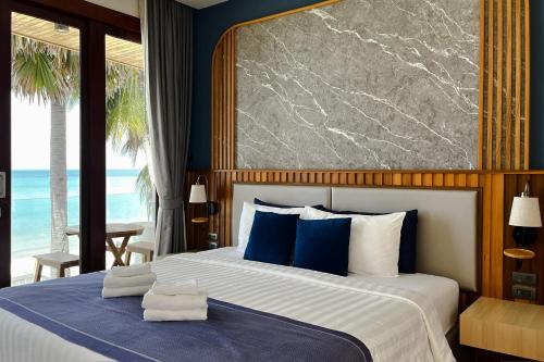 a bedroom with a large bed with blue and white pillows at เดอะซีน คาบาน่า บีช รีสอร์ท ขนอม The Scene Cabana Beach Resort Khanom in Ban Plau