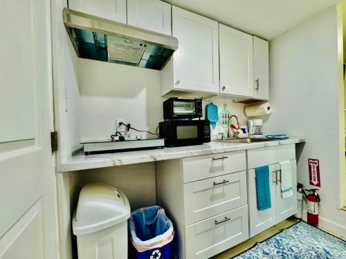 a small kitchen with white cabinets and a microwave at 1 Bedroom Mini Apartment 10 Minutes to SeaTac Airport 1 Minute Walk to Bus Station in Seattle