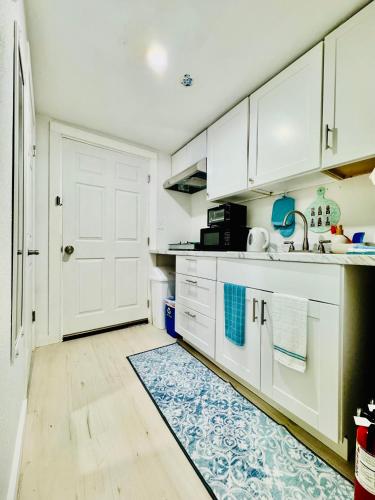 a kitchen with white cabinets and a blue rug at 1 Bedroom Mini Apartment 10 Minutes to SeaTac Airport 1 Minute Walk to Bus Station in Seattle