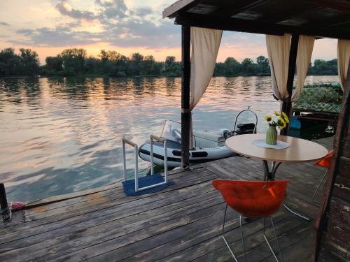 a dock with a table and a boat on the water at Zmajevo Gnezdo II Water House in Beograd