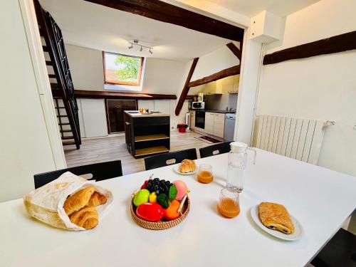 a table with a bowl of fruit and bread on it at Gîtes Montvaltin - Appartement spacieux 3 chambres & cuisine in Le Breuil