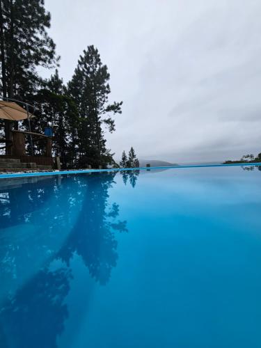 ein blauer Pool mit Bäumen im Hintergrund in der Unterkunft Cabana Vita Bella in Nova Trento
