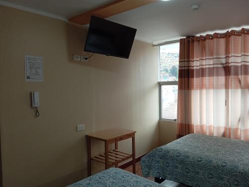 a bedroom with two beds and a television on the wall at Casa del Virrey Hospedaje in Jauja