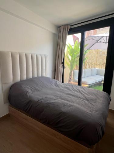 a bed in a room with a large window at Sunny apartment la huerta in Alicante