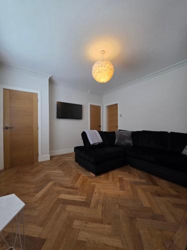 a living room with a black couch and a television at The City Haven Near City Centre in York