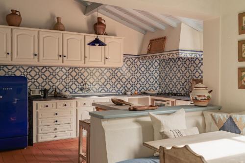 a kitchen with white cabinets and blue tiles at CABRA - Porto Covo in Porto Covo