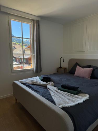 a bedroom with a large bed with a window at Comfy, Spacious and Central Duplex Apartment in Zweisimmen