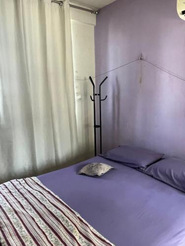 a bedroom with a bed with violet sheets and a window at Quarto em apartamento em Belem in Belém