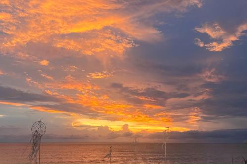 a sunset over the ocean with a cloudy sky at เดอะซีน คาบาน่า บีช รีสอร์ท ขนอม The Scene Cabana Beach Resort Khanom in Ban Plau