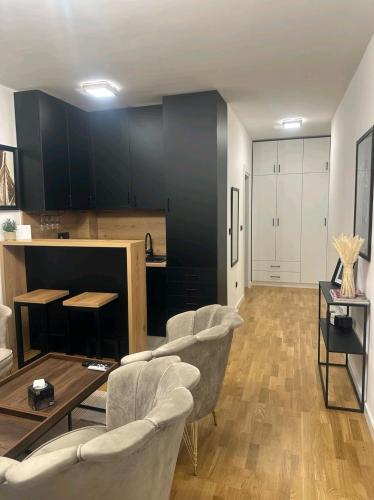 a living room with chairs and a table and a kitchen at Apartman Nia in Priboj