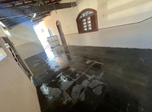 an empty room with a black floor and a window at Casa Temporada in Rio das Ostras