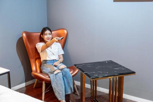 a woman sitting in a chair looking at her cell phone at 12번길stay 