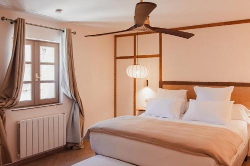 a bedroom with a large bed with a ceiling fan at La suite Kyoto, appartement privé Uzès in Uzès