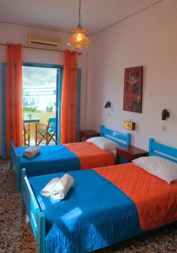 a bedroom with two beds and a window with a table at Chrissi Ammos in Perissa