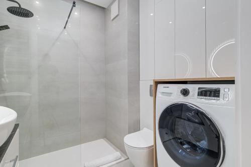 a washing machine in a bathroom next to a toilet at Perfect Location - Modern Riverside Apartment in Warsaw