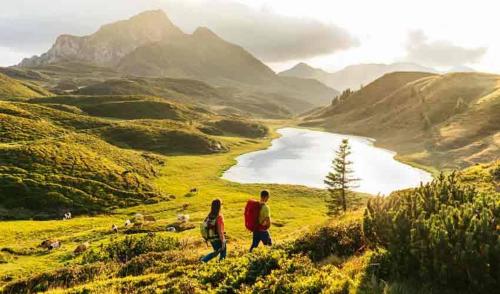 a man and woman walking on a hill overlooking a lake at Alpine Oasis in Hermagor
