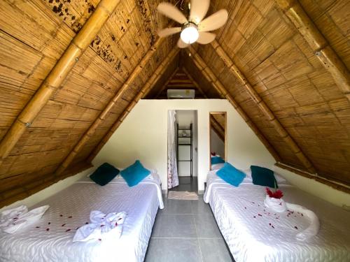 two beds in a room with a ceiling at Eco Hotel Amanecer Tayrona in El Zaino