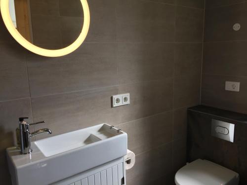 a bathroom with a sink and a toilet and a mirror at Lindartún Guesthouse in Lindartún
