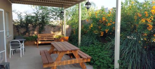 a patio with a wooden table and a bench at נצר- צימר אירוח כפרי in Kerem Shalom