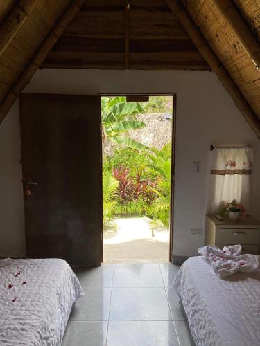 a bedroom with a door open to a garden at Eco Hotel Amanecer Tayrona in El Zaino