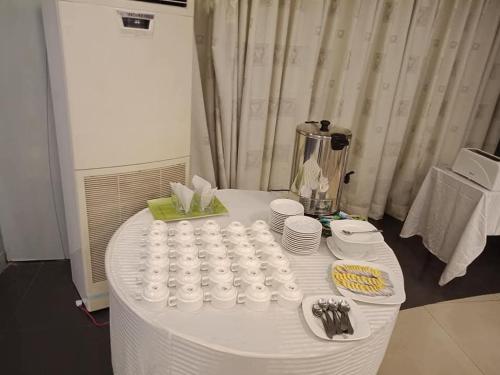 a white table with cups and plates on it at New Al-Safina Hotel in Lahore