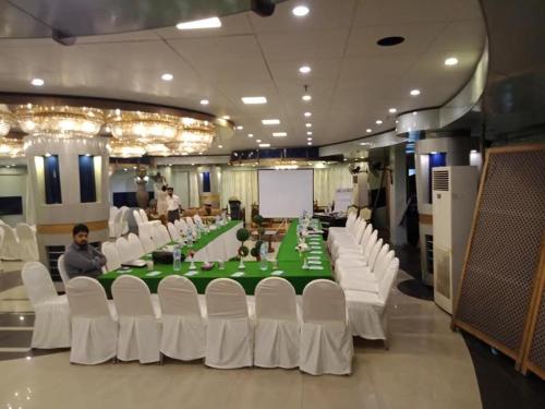 a conference room with a green table and white chairs at New Al-Safina Hotel in Lahore