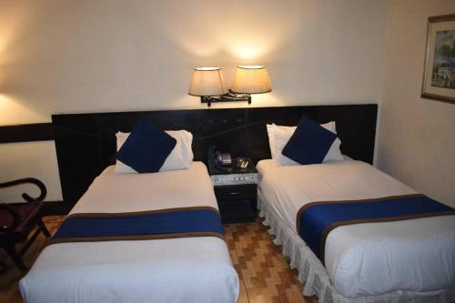 two beds in a hotel room with blue pillows at New Al-Safina Hotel in Lahore