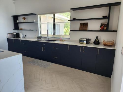 a kitchen with dark blue cabinets and a window at Rock House Estate in Bequia
