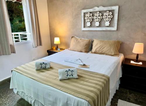 a bedroom with a large bed with two pillows on it at Pousada Tortugas in Guarujá
