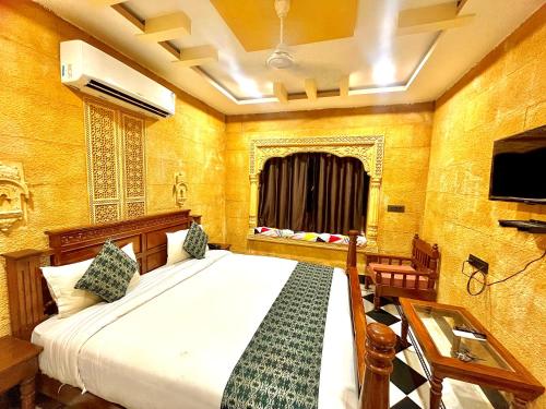 a bedroom with a bed and a table and a tv at Hotel Queen Royal Jaisalmer in Jaisalmer