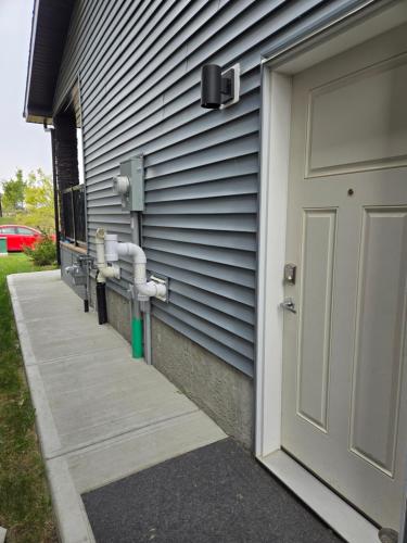 エドモントンにあるParkside Basement Suiteの側面にパイプがある家のドア