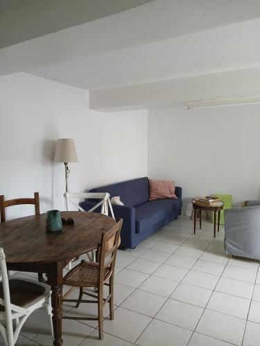 a living room with a blue couch and a table at Maison lac in Pouzauges