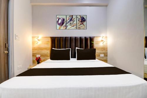 a bedroom with a large white bed with black pillows at Hotel O Gold Inn in Rohtak