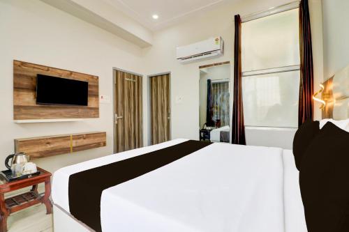 a bedroom with a bed and a tv on a wall at Hotel O Gold Inn in Rohtak