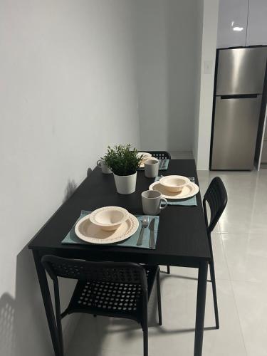 a black table with plates and chairs and a refrigerator at JC Apartment - One bedroom in Toa Baja