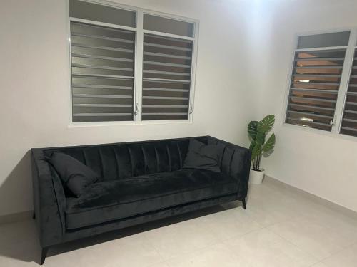 a black couch in a living room with two windows at JC Apartment - One bedroom in Toa Baja