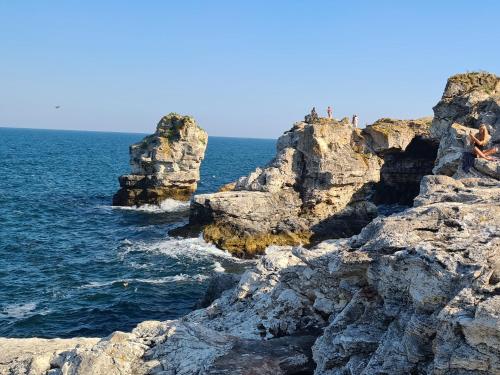 a group of people sitting on rocks near the ocean at Villa Bellavista in Kavarna