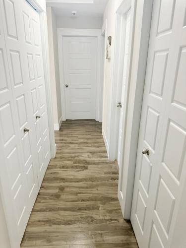 a hallway with white doors and wood floors at Private Home Near Moncton Hospital&Downtown in Moncton