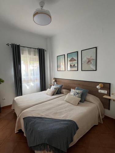 two beds in a white room with a large window at El Paraíso de Isla Canela in Isla Canela
