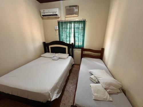 two beds in a small room with a window at Hotel Brisa do Araguaia SFA in São Félix