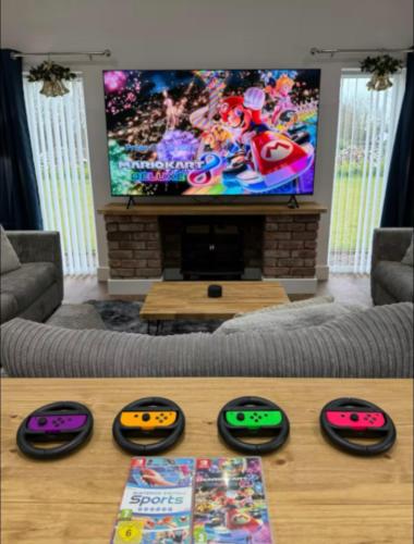 a living room with a tv and four controllers at Oak View at Moss Bank Farm in Wrexham