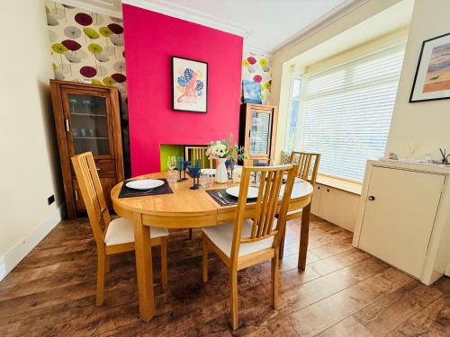 a dining room with a wooden table and a pink wall at Last-Minute Reserve l Exclusive Deal l Sleeps Up to 5 l Free Parking l cottage l close to city in Birmingham