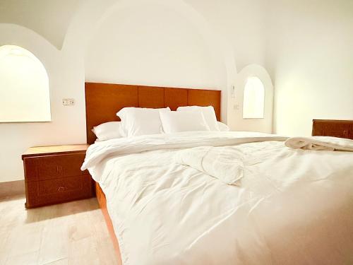 a large white bed in a bedroom with two windows at Bab Al Shams Palace in Luxor