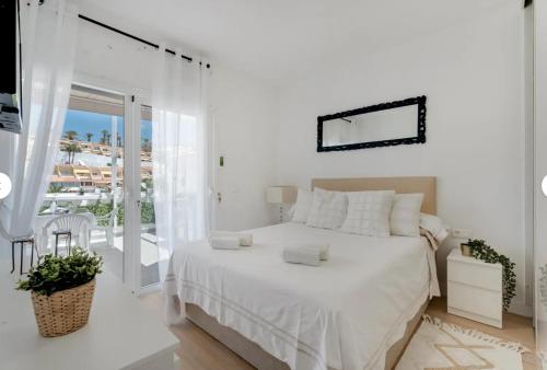 a white bedroom with a bed and a balcony at Sun Garden in Adeje