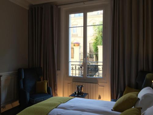 a bedroom with a bed and a window and a chair at La Suite 19 in Saint-Mandé