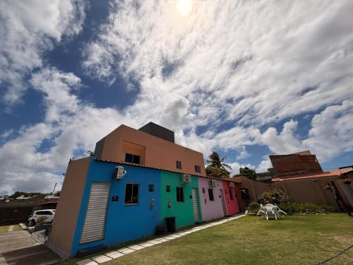 a colorful house with a cloudy sky in the background at Suíte Porto das Dunas in Salvador