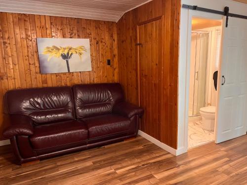 a brown leather couch in a room with a bathroom at Camping Chalets Lac St-Augustin in Quebec City
